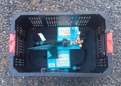 High-pressure sprinkler tool with hoses, mounted on black plastic basket, for wildfire safety; used with Wildfire Watchdog's automated detection and sprinkler systems in Bend, Oregon.