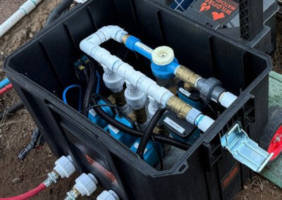 Flexible, automated wildfire sprinkler system in a black control box with white, blue, and brass fittings, designed for property protection in Bend, Oregon by Wildfire Watchdog.
