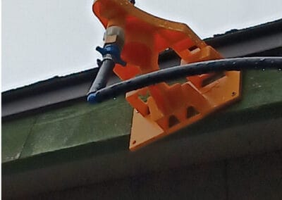 High-angle view of an orange wildfire detection and sprinkler system mounted on a building roof, with connected piping and electrical components, in Bend, Oregon.